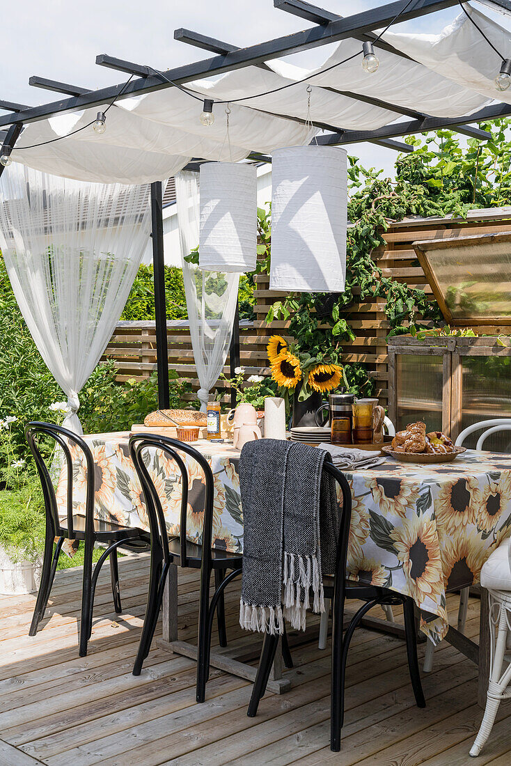 Dining table with chairs under pergola on terrace