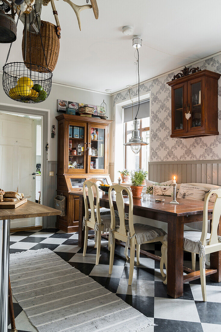 Holztisch mit Stühlen und antiker Vitrinenschrank in der Küche mit Schachbrettfliesen