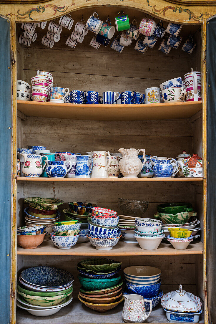 A selection of brightly coloured crockery in an old wooden cupboard