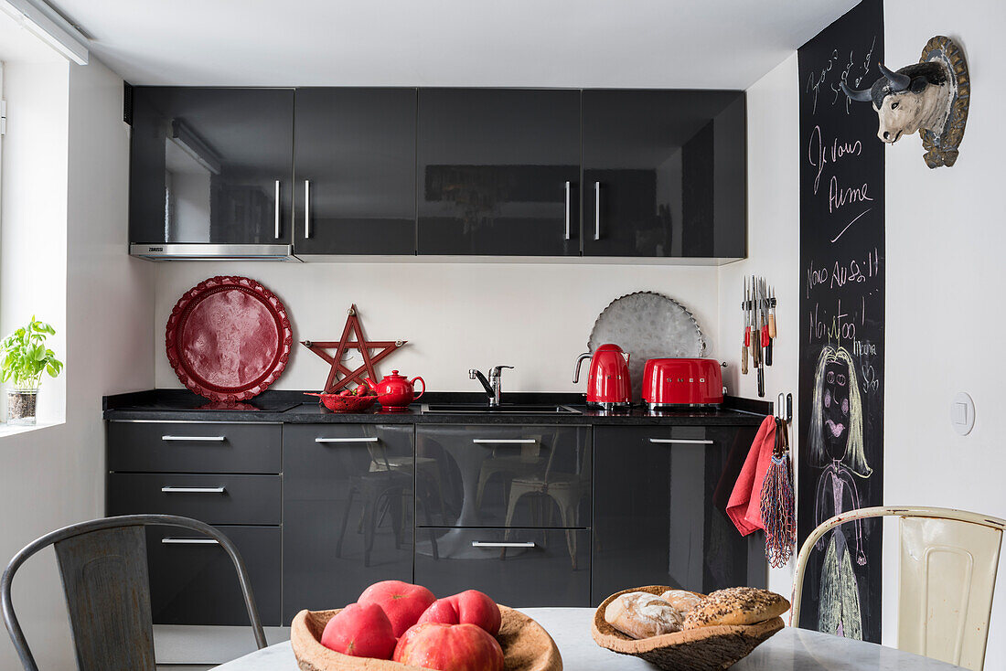 Rote Deko als Farbakzent in grau-weißer Wohnküche mit Wandtafel