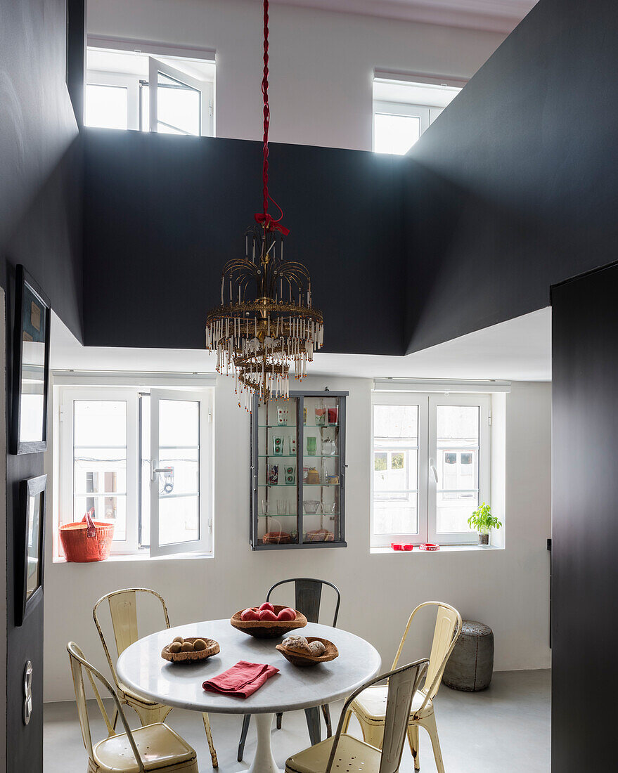 Chandelier above dining table in modern interior with gallery level