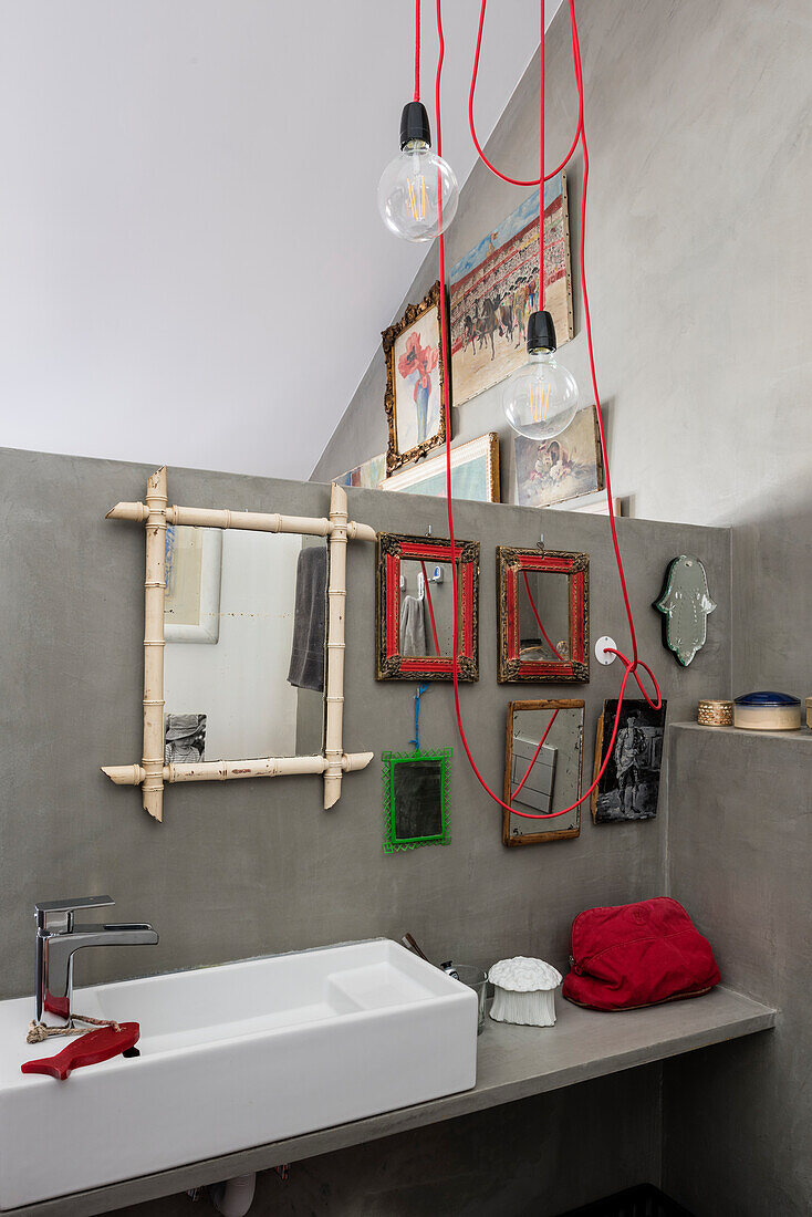 Leuchte mit roten Kabeln im Bad mit Spiegelsammlung an grauer Wand
