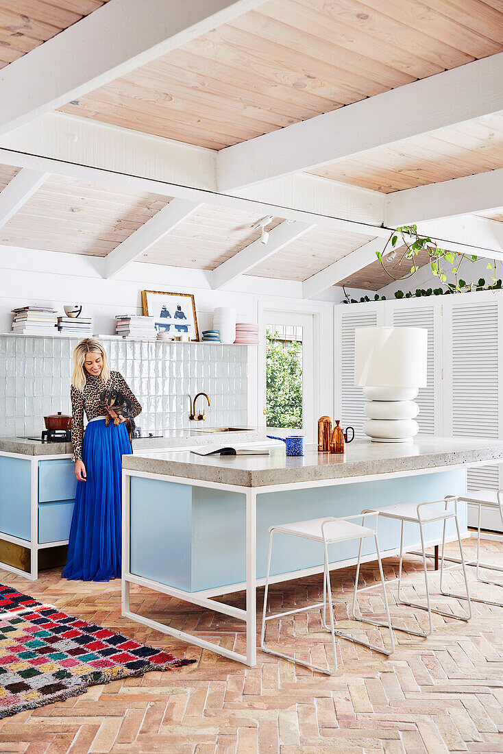 Woman with dog in open kitchen, kitchen island with bar stools