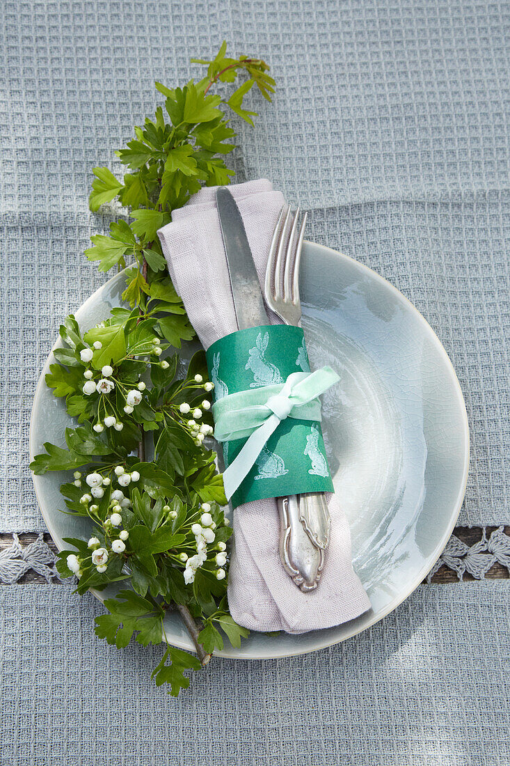 Easter place setting with DIY napkin ring and sprig of hawthorn