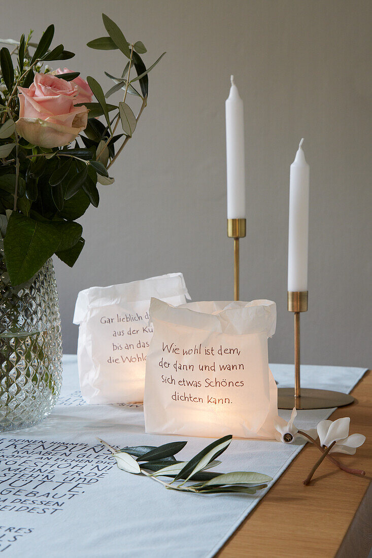 Beschriftete Papiertüten als Windlichter, Kerzen und Blumenstrauß