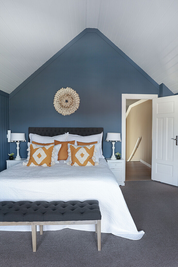 Doppelbett und Kleiderbank im Schlafzimmer mit blauer Wand im Dachgeschoss