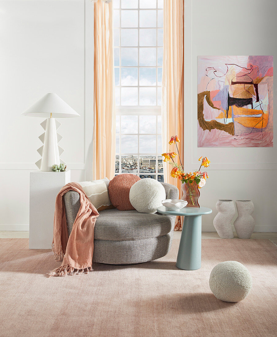 Feminine living room in pastel shades with grey armchair in front of the window