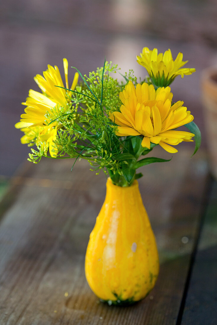 Small bouquet of marigolds and fennel flowers in an ornamental pumpkin as a vase