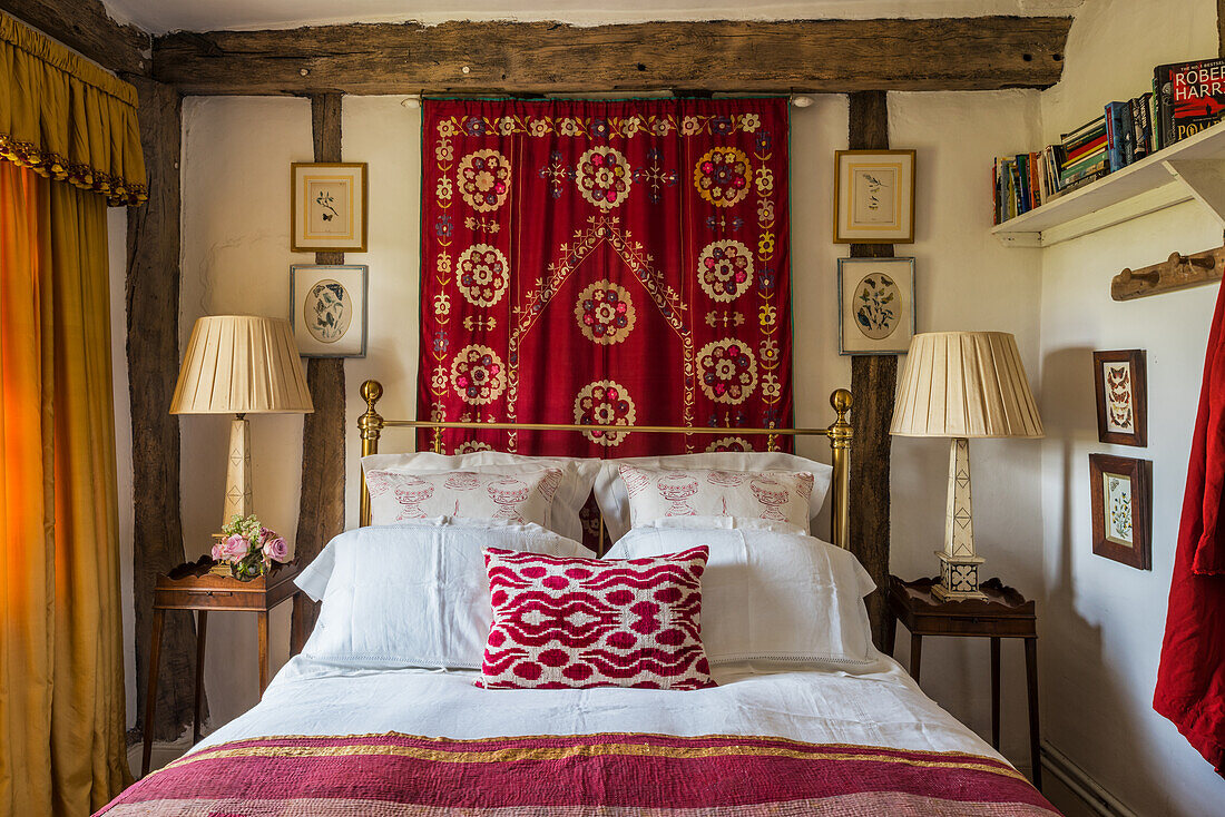 Doppelbett vor Wandbehang im Gästezimmer mit rustikalen Holzbalken
