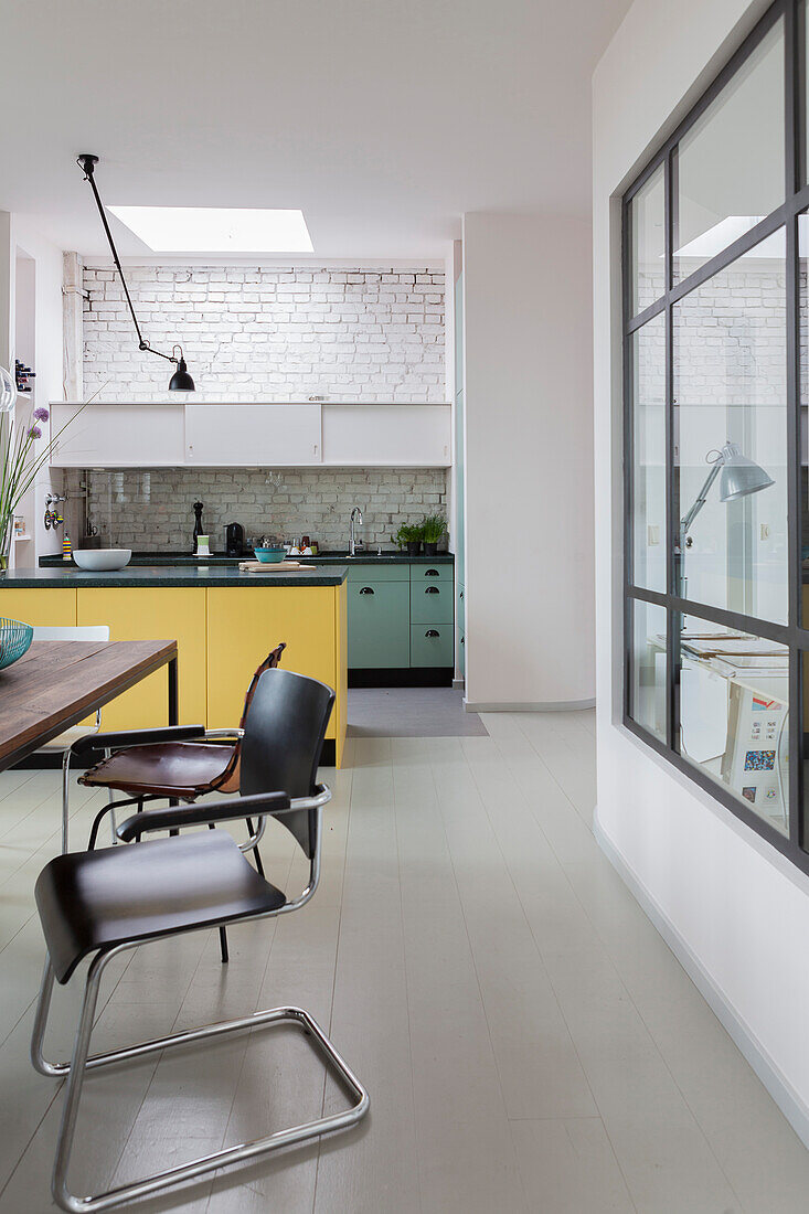 Cantilever chair at dining table in front of open-plan kitchen