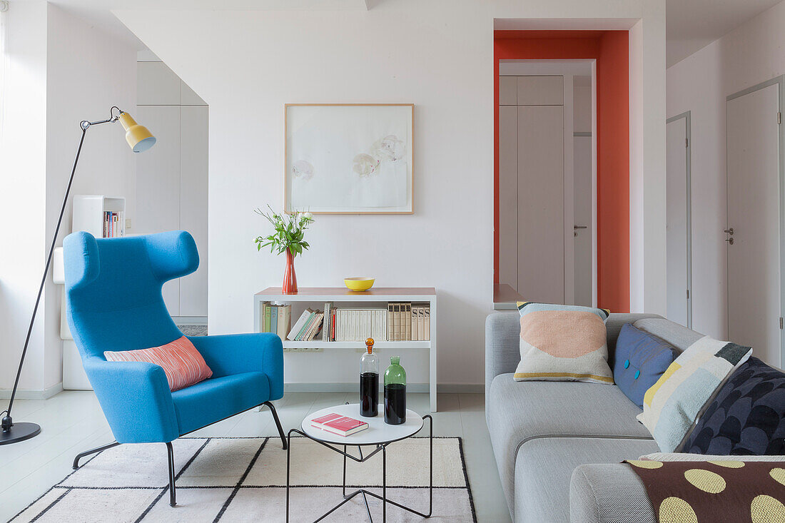 Blue wing-back chair, coffee table and grey sofa in open-plan interior
