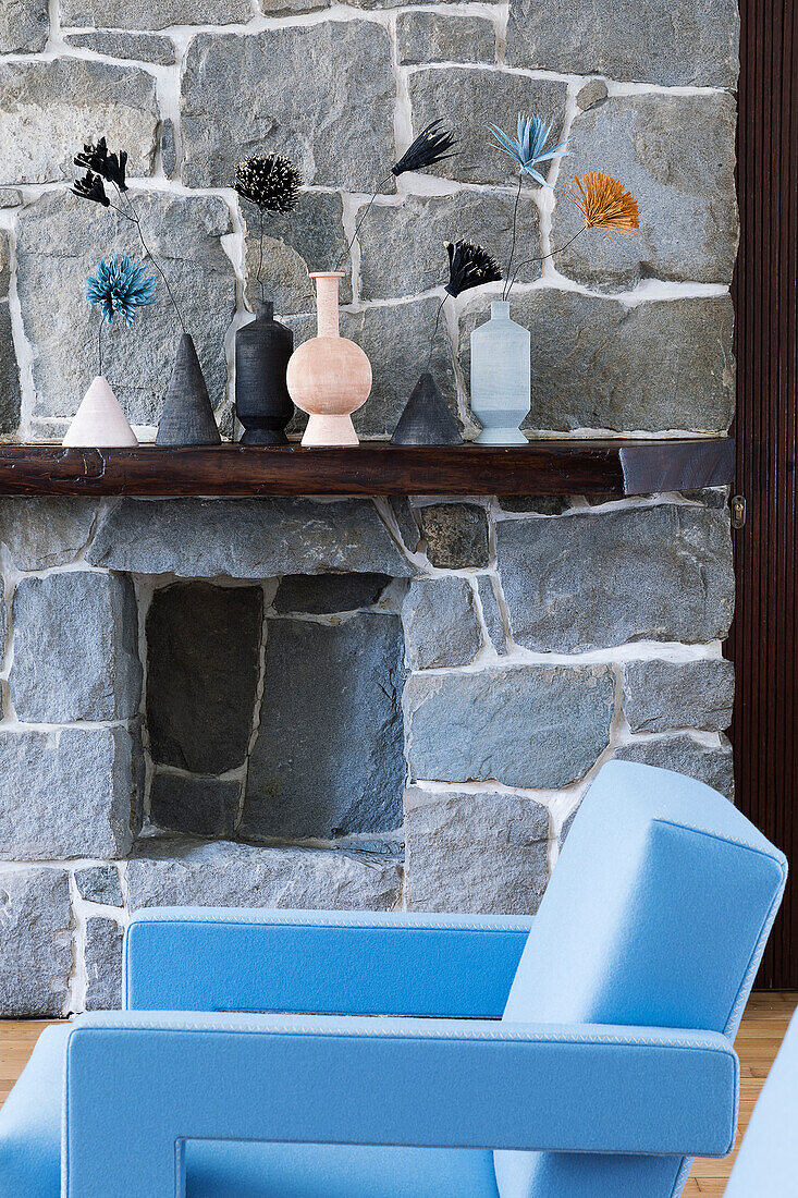 Hellblauer Designersessel vor Natursteinwand im Wohnzimmer