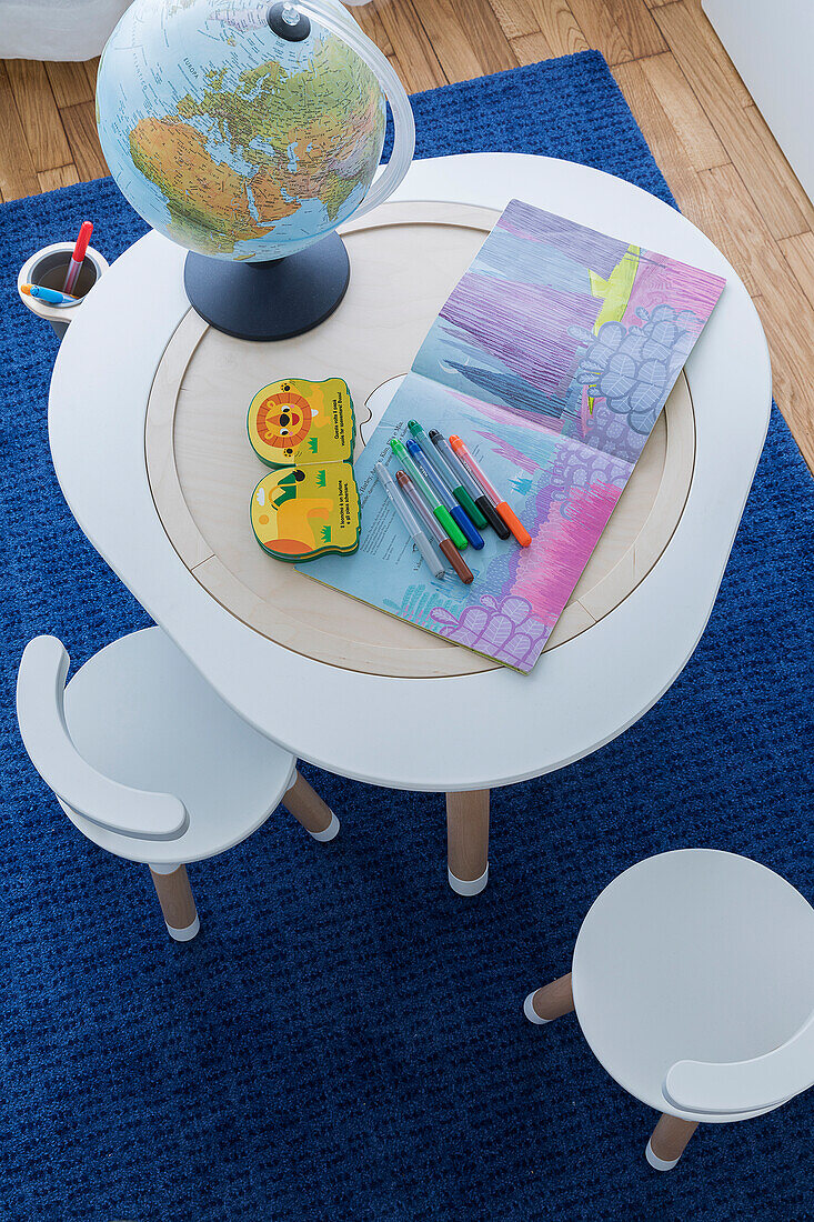 Colouring book with pens and globe lamp on children's table