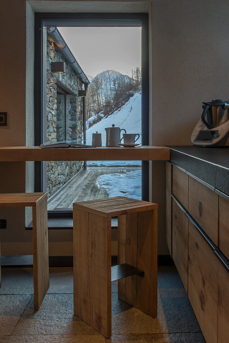 Frühstückstheke und Barhocker aus Massivholz vor Panoramafenster