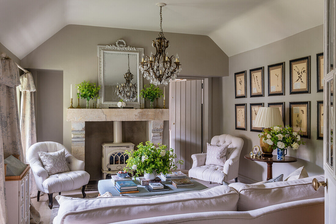 Weiße Polstermöbel, Holzofen und botanische Drucke im Wohnzimmer mit hellgrauen Wänden