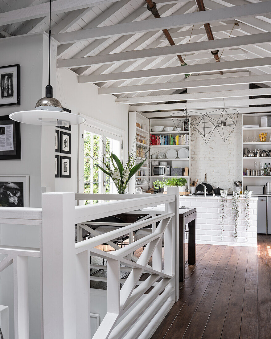 Dining table in white kitchen in country house with open roof structure