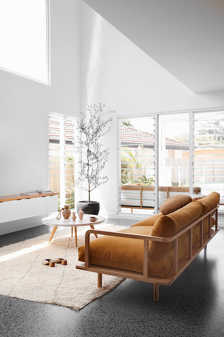Braunes Sofa mit Samtpolster und Coffeetable in hellem, hohem Wohnraum