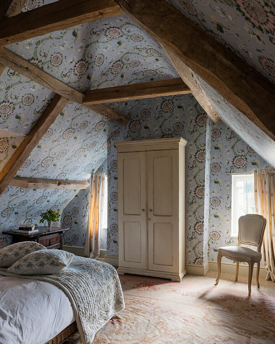 Light blue papered timber framed attic bedroom with cream wardrobe