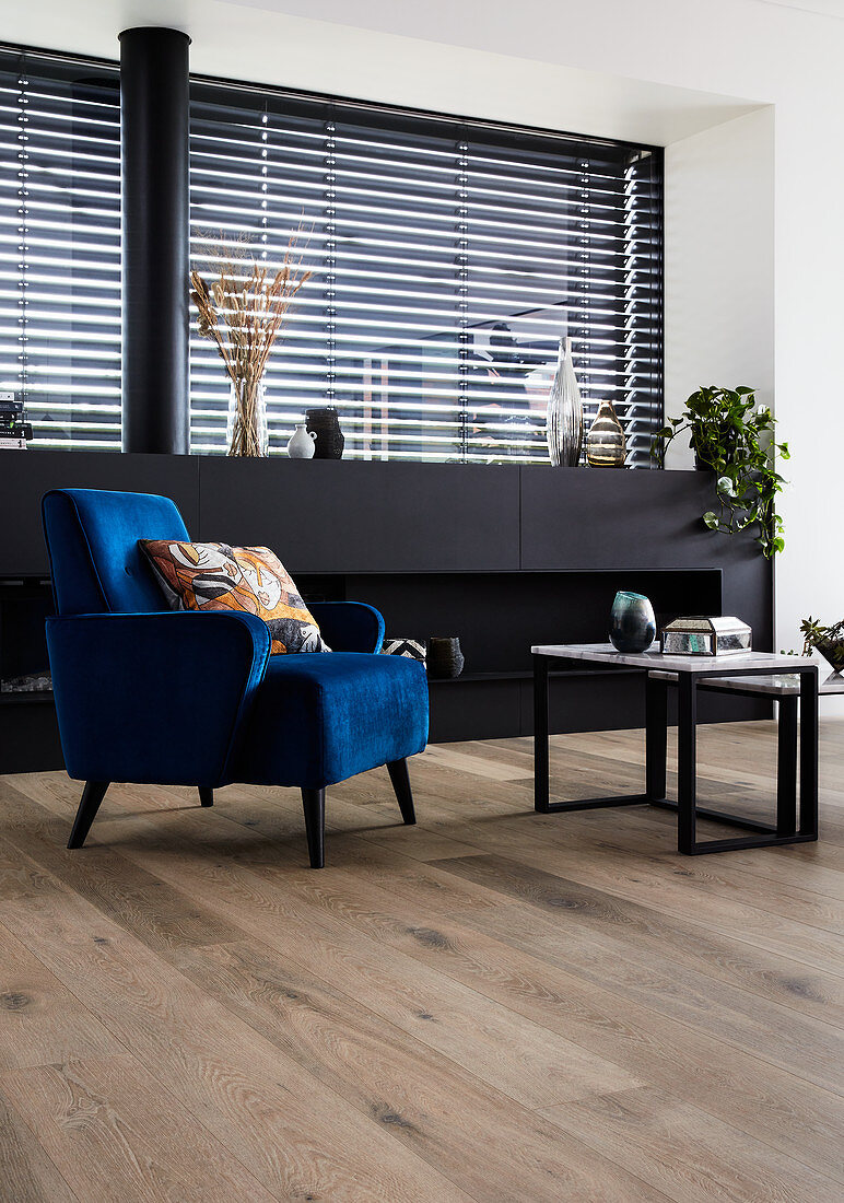 Blue velvet armchair in front of black sideboard in living room