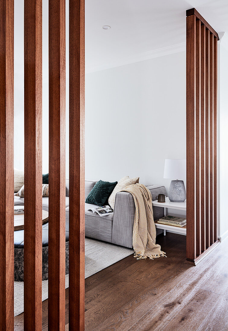 Blick durch Raumteilerwände aus Holz ins Wohnzimmer