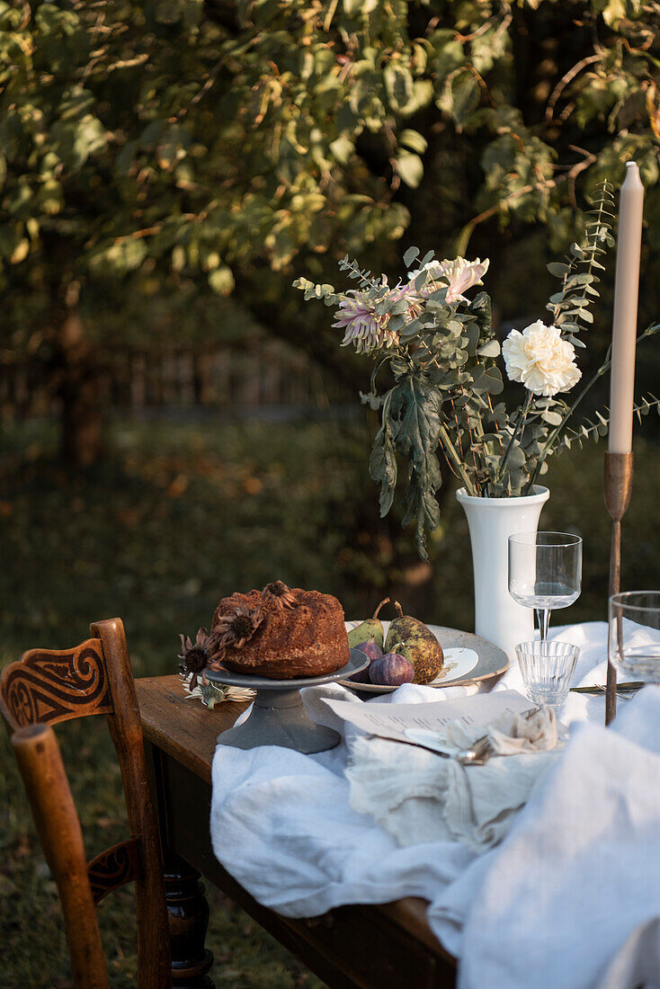 Gugelhupf und Blumen auf festlich gedecktem Tisch im Garten