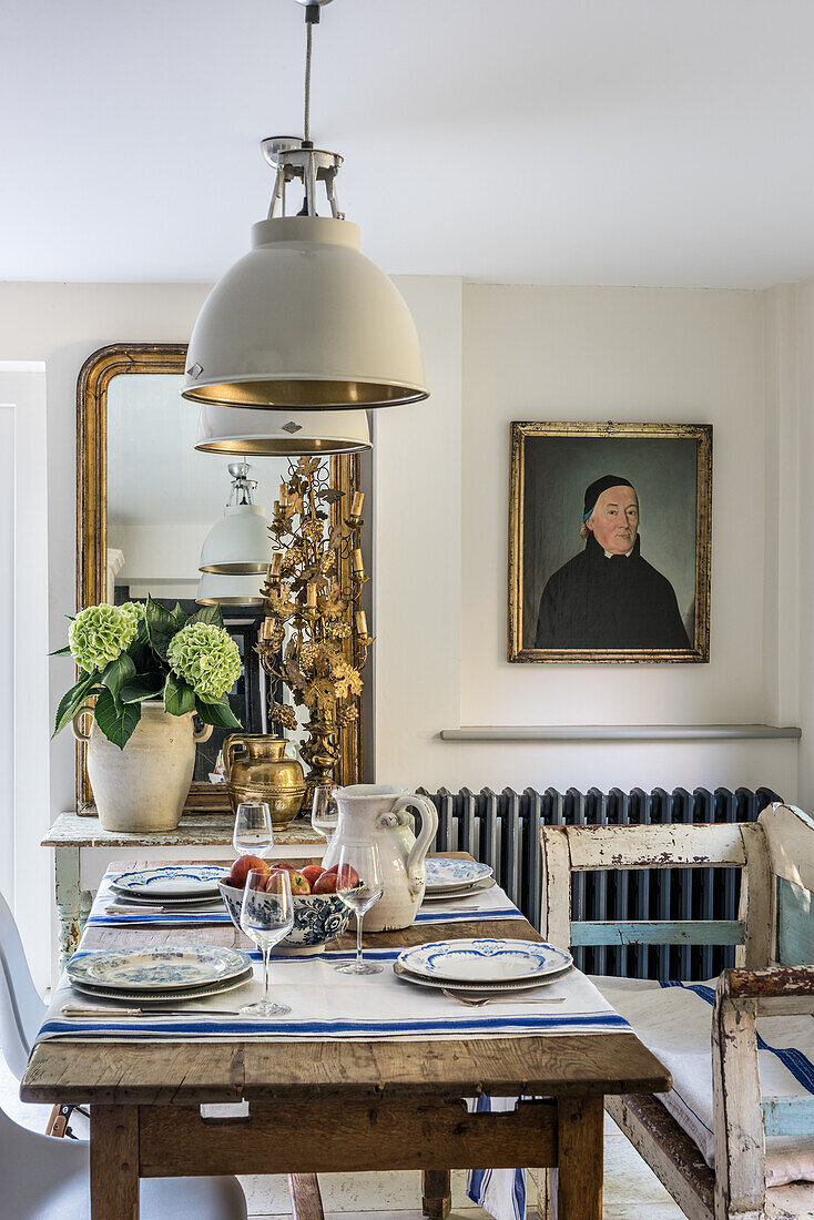 19th century portrait of a French priest is informal dining area with oak table and Hungarian bench seat