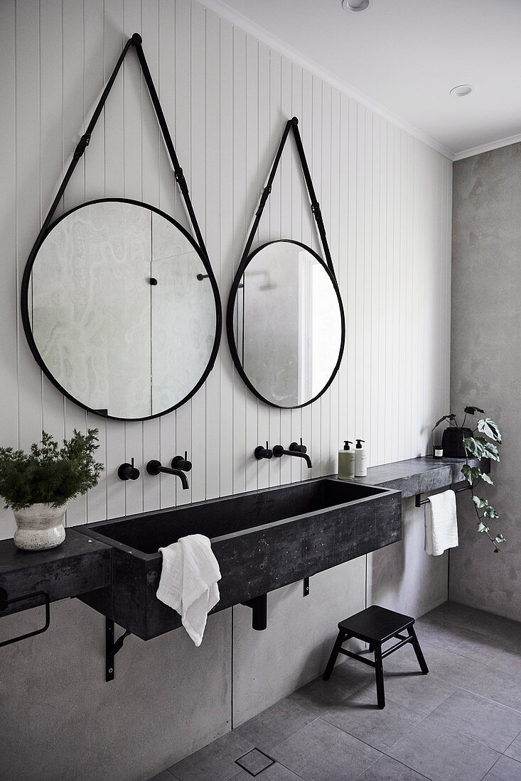 Zwei runde Spiegel überm modernen Waschbecken im grauen Bad