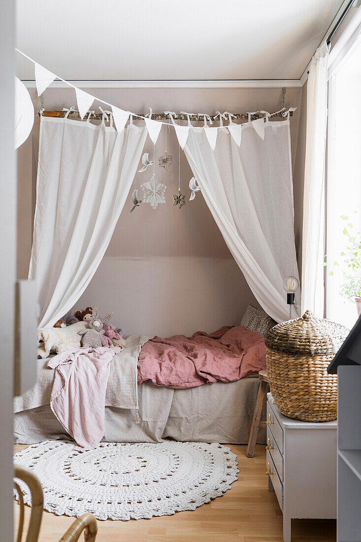 Bett mit Vorhang und runder Teppichvorleger im Mädchenzimmer in gedeckten Farben