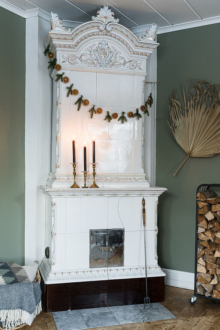 Weißer Kachelofen mit Kerzen und Weihnachtsgirlande in Zimmerecke
