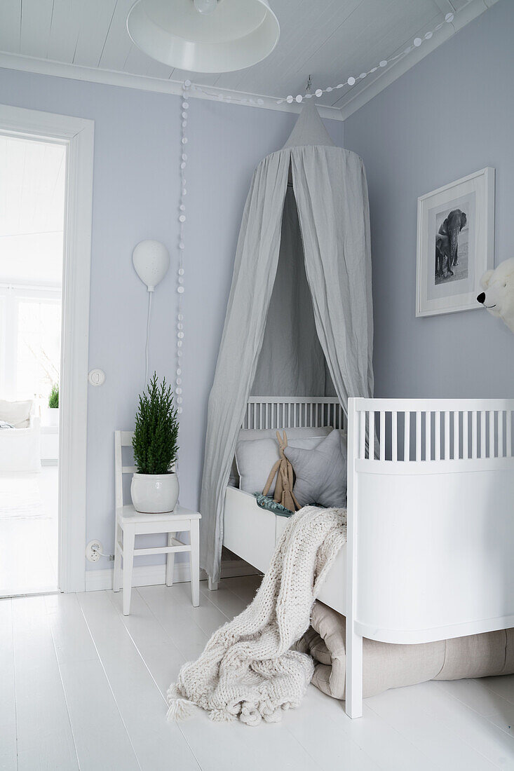 White wooden cot with canopy in light-blue nursery