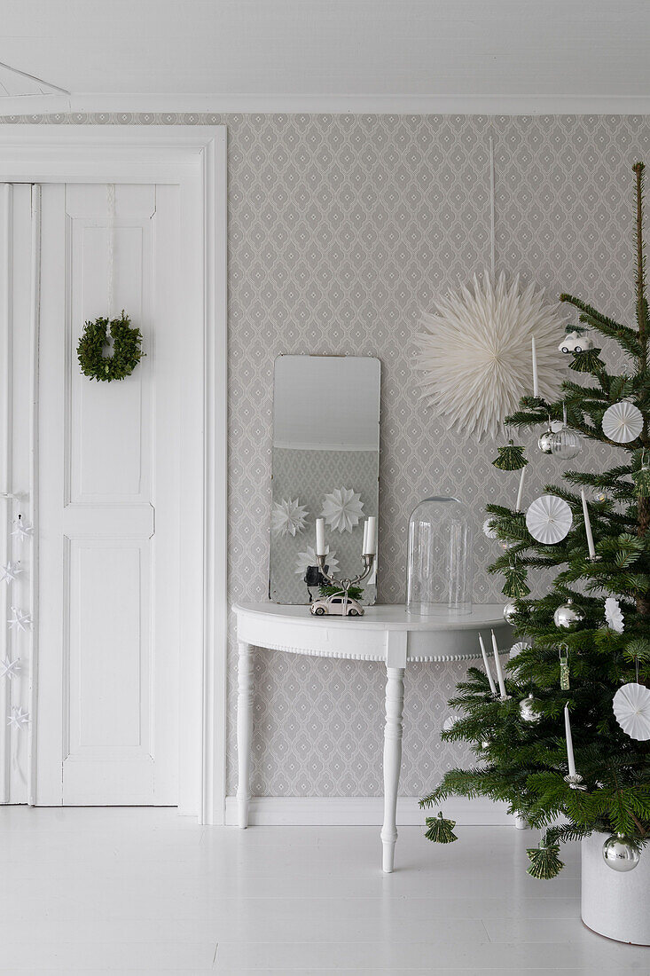 Weihnachtsbaum und Konsolentisch mit Spiegel vor tapezierter Wand