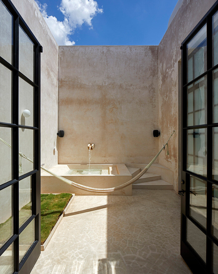 Double doors leading into Mediterranean courtyard with fountain and hammock