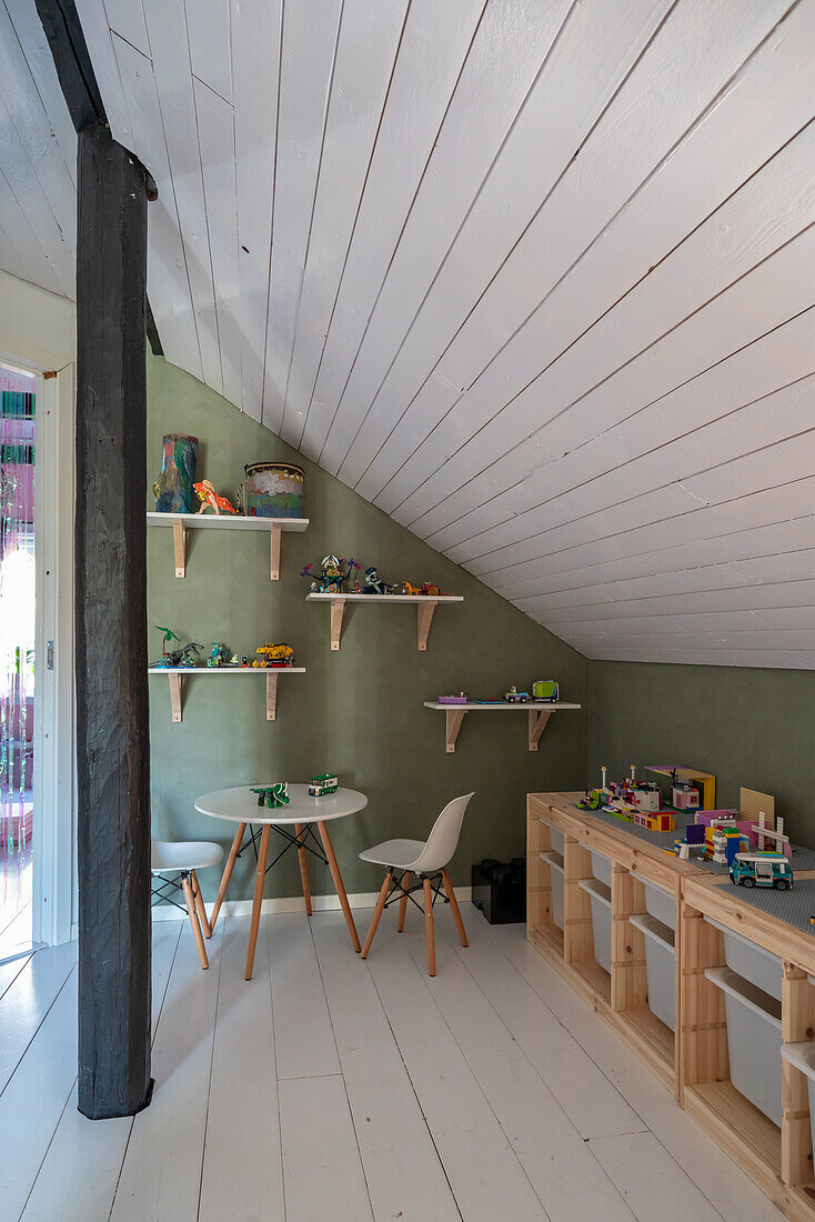 Regale mit Spielsachen, Kindertisch und Stühle im Dachzimmer
