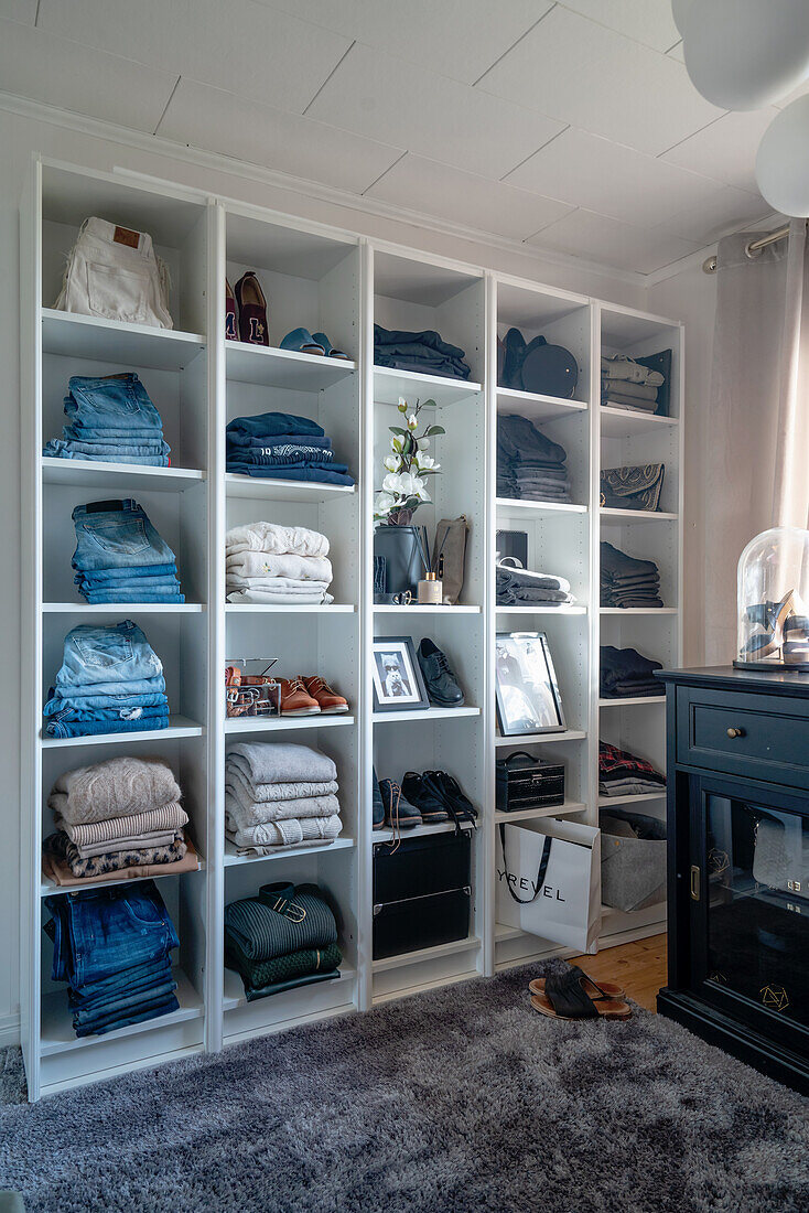 Organized neat clothes on white shelves in a dressing room