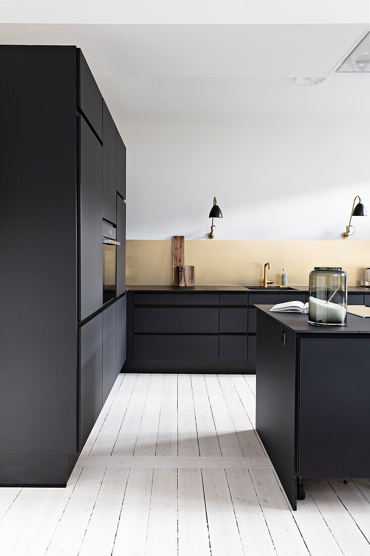 Moderne schwarze Küche mit goldenem Spritzschutz