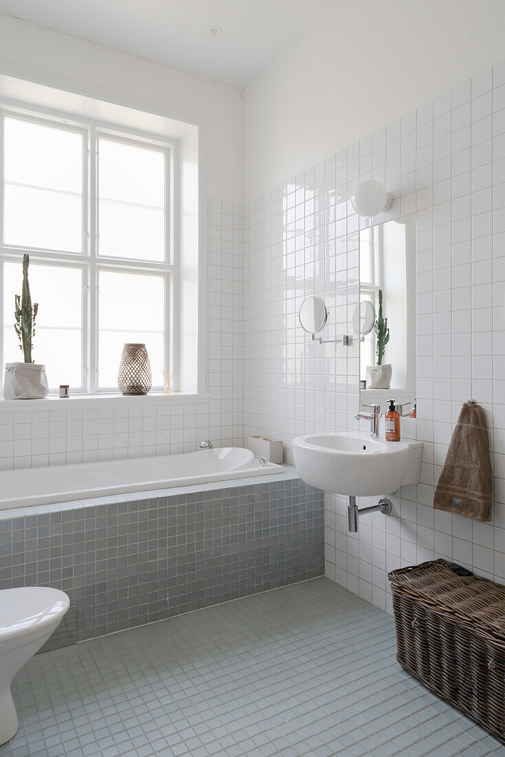 Bright, tiled bathroom with bathtub and window