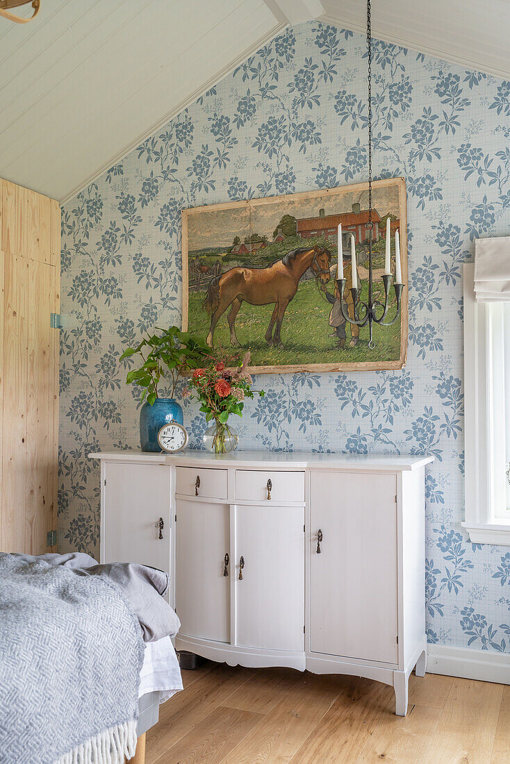 Weiße Kommode, darüber Bild mit Pferd im Schlafzimmer mit blauer Tapete