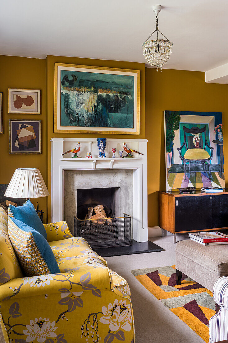 Gelbes Sofa, Kamin und Gemäldesammlung an senfgelber Wand im Salon