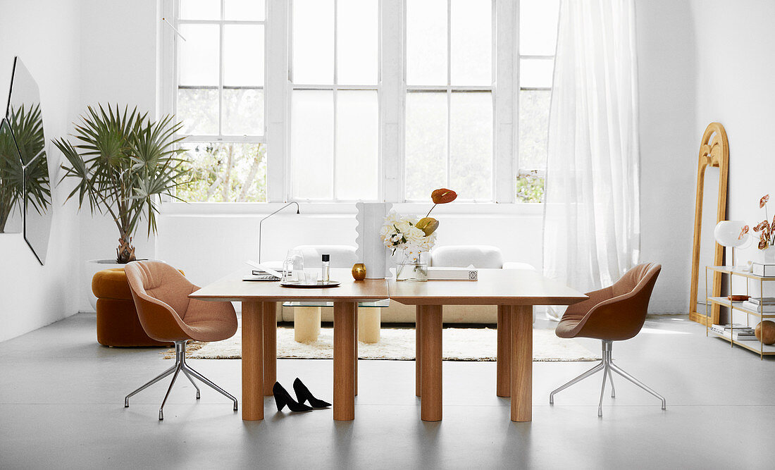 Doppeltische mit eleganten Schalenstühlen in weißer, luftiger Ambiente