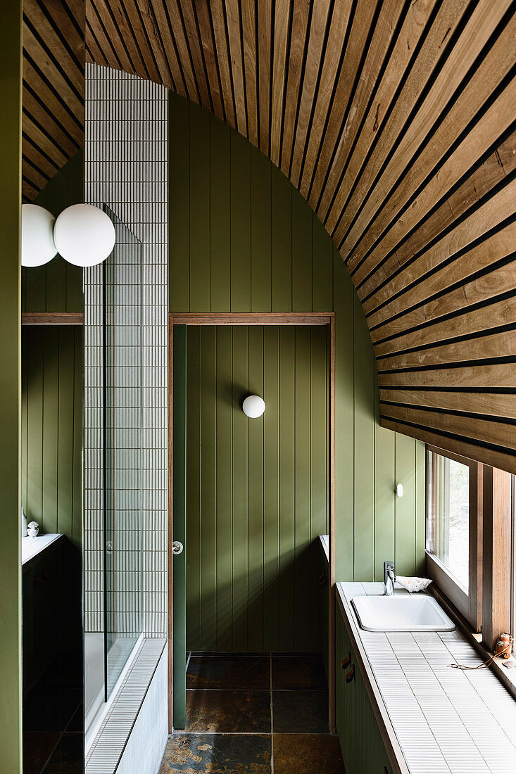 Narrow bathroom with green wood panelling and curved wooden ceiling