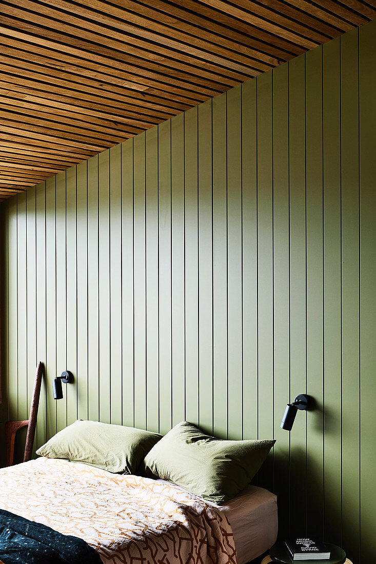 Double bed in bedroom with green-painted wood panelling