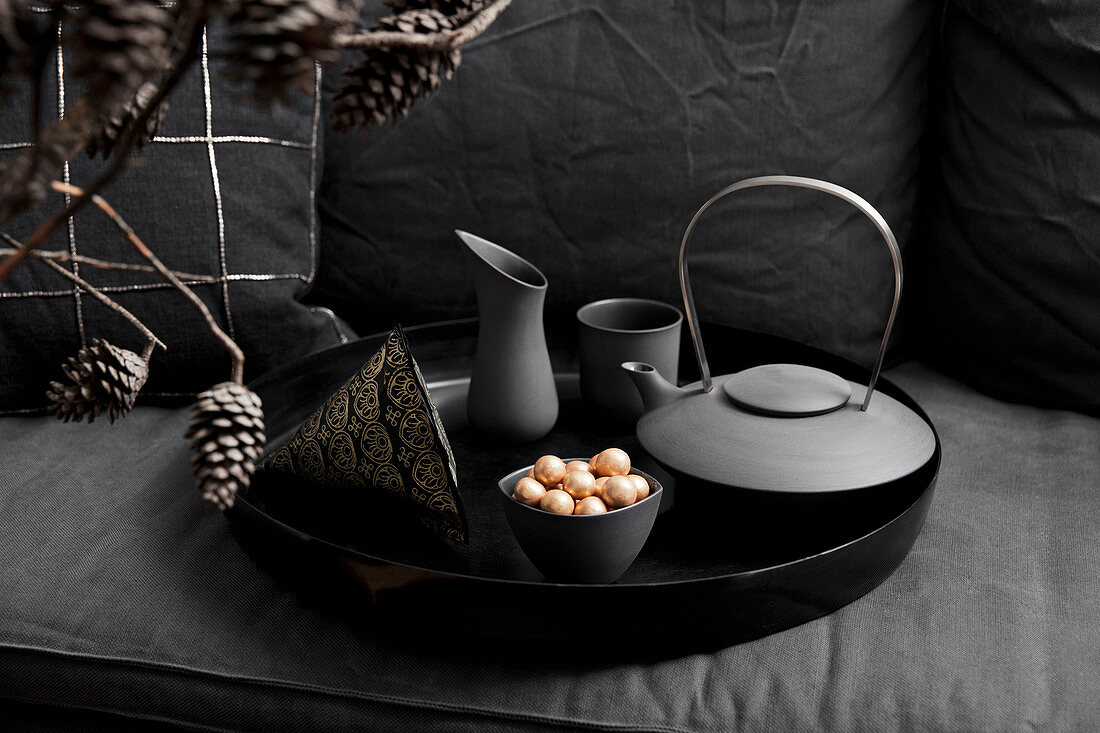 Teekanne und Gefäße auf schwarzem Tablett