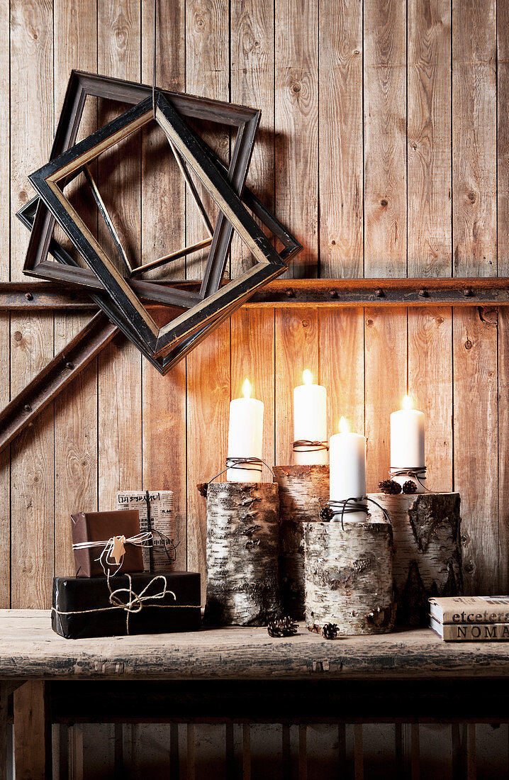 Alte Bilderrahmen und Holzbank mit brennenden Kerzen vor rustikaler Bretterwand