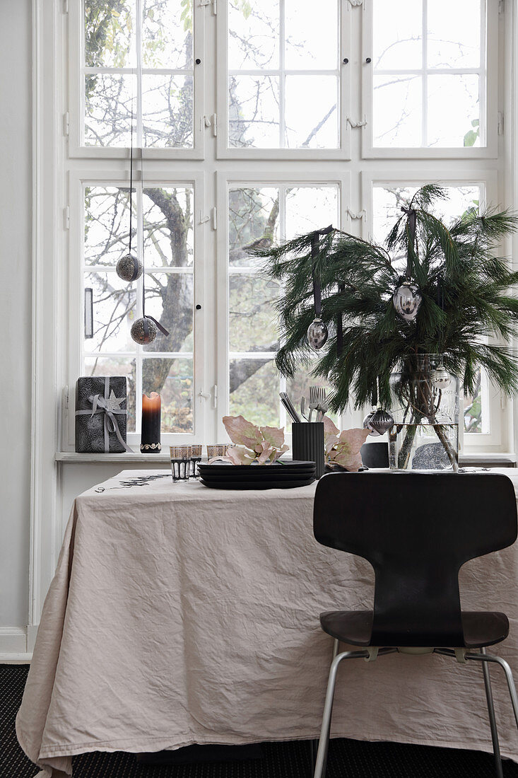 Schwarzer Stuhl am weihnachtlich gedecktem Tisch mit heller Tischdecke