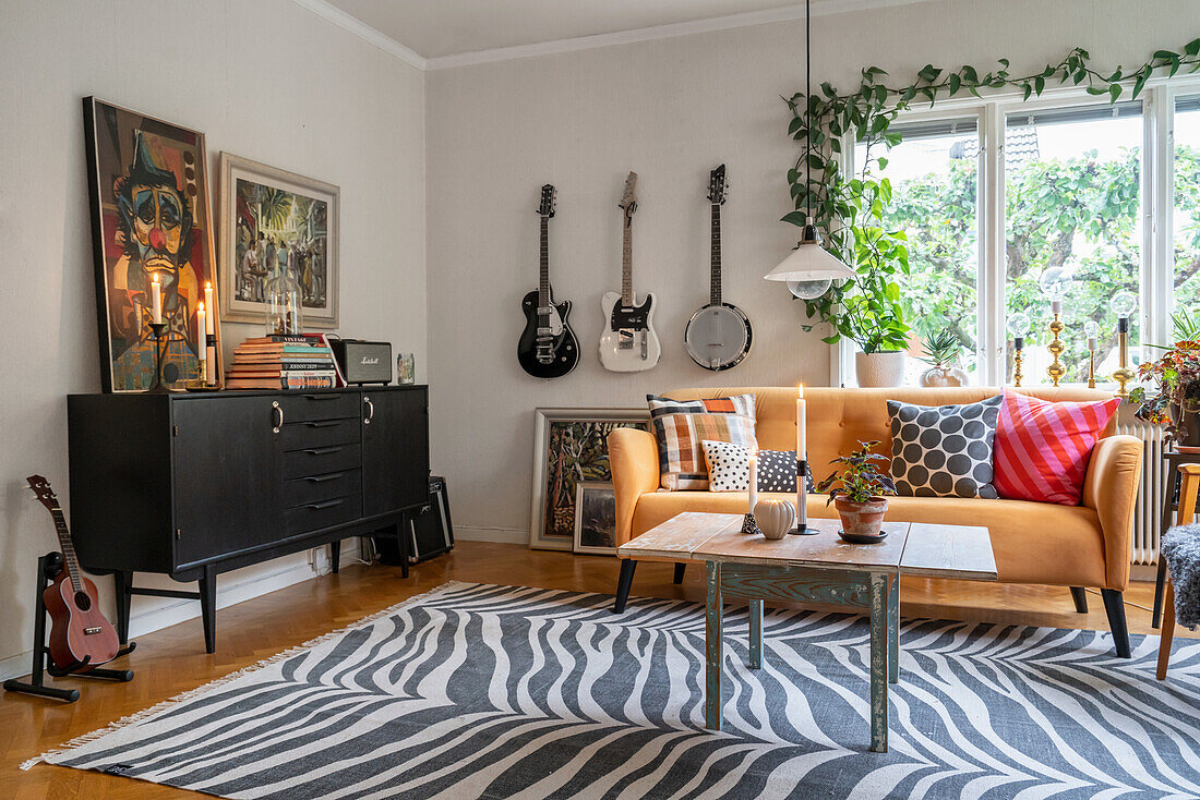 Black sideboard, yellow sofa and guitars in living room