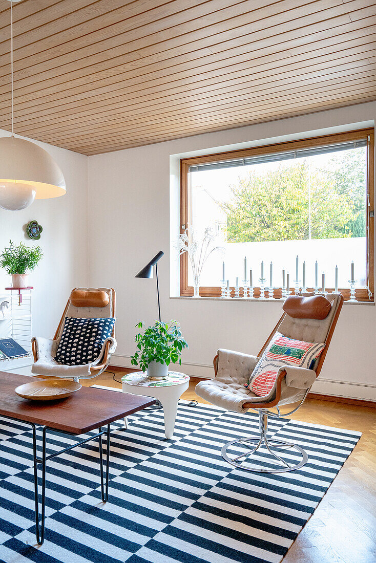 Retro Sessel au schwarz-weiß gestreiftem Teppich in hellem Wohnzimmer