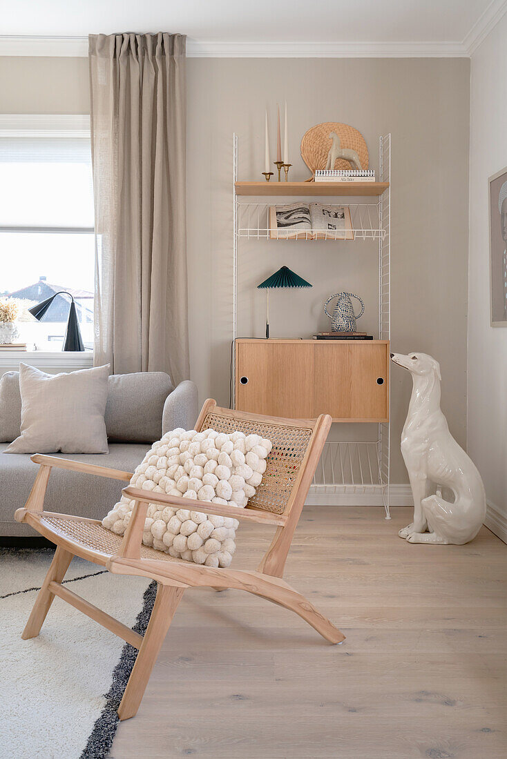 Beige living room with dog statue, shelves and designer chair in the foreground