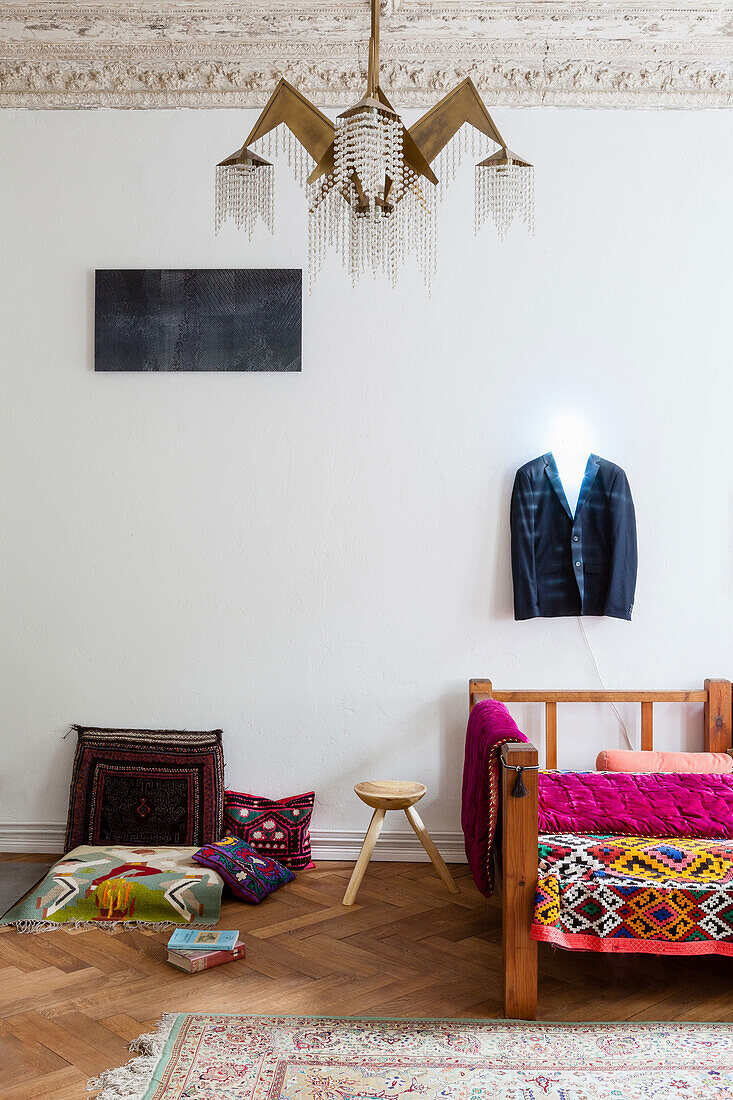 Colourful blanket on sofa with wooden frame, coat hanger above with neon light