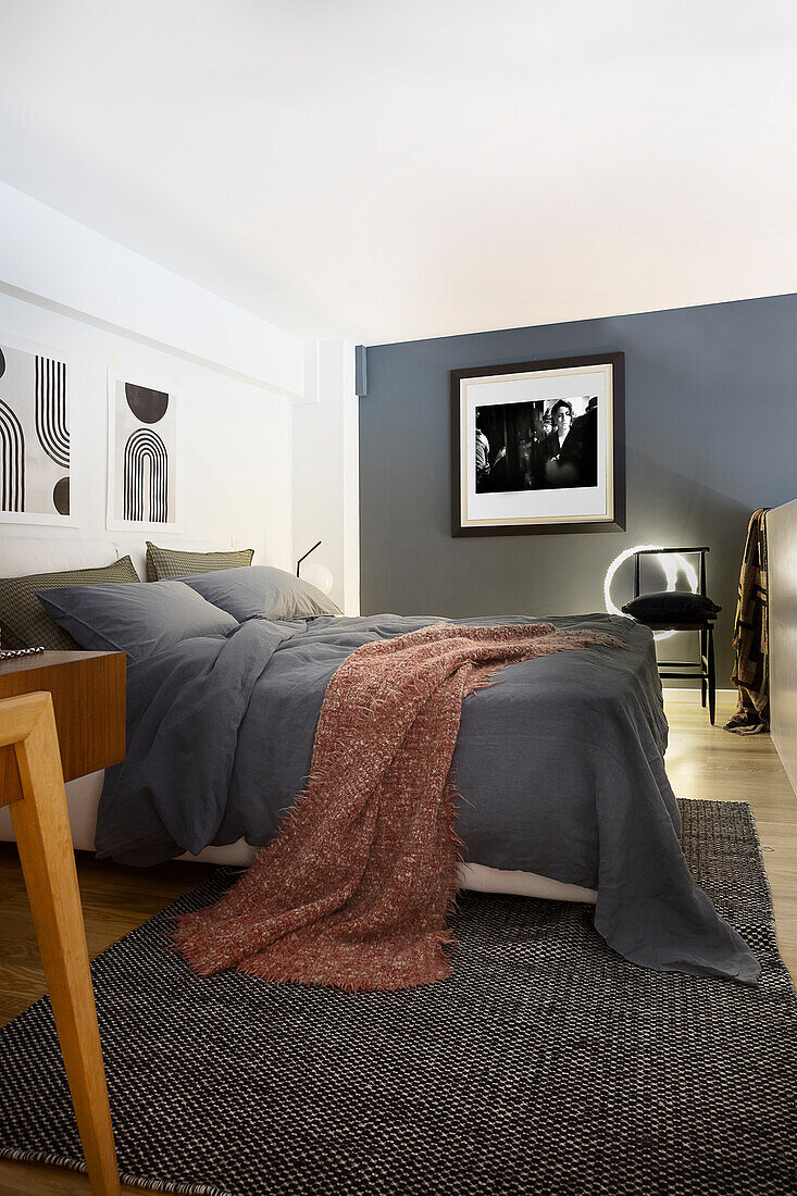 Queen bed with gray bedding and throw in bedroom