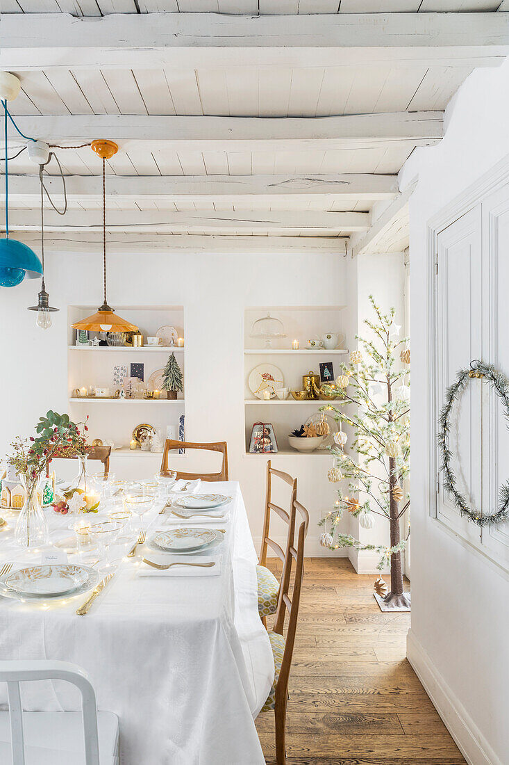 Weiß gedeckter Weihnachtstisch in ländlichem Speisesaal